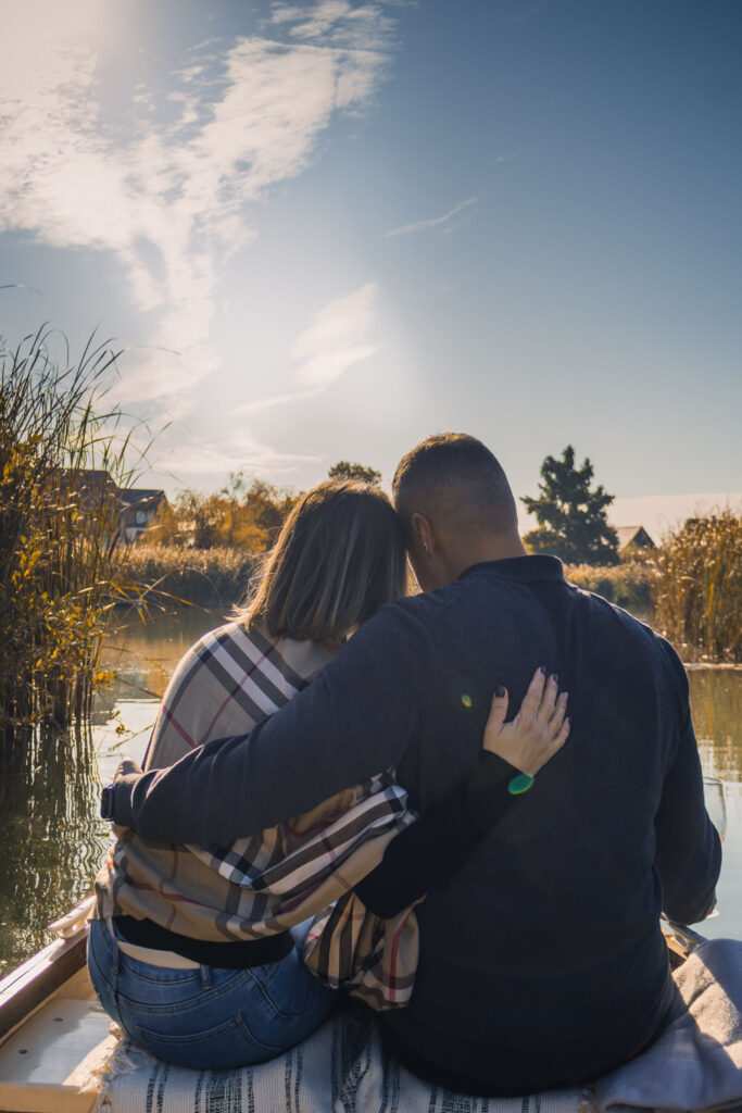 Pár csókolózik egy hajón a naplementén, romantikus esküvői fotó.